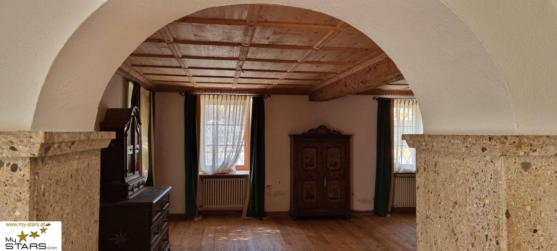 Geräumiger Raum mit Holzkassettendecke, Bogen und traditionellen Möbeln.