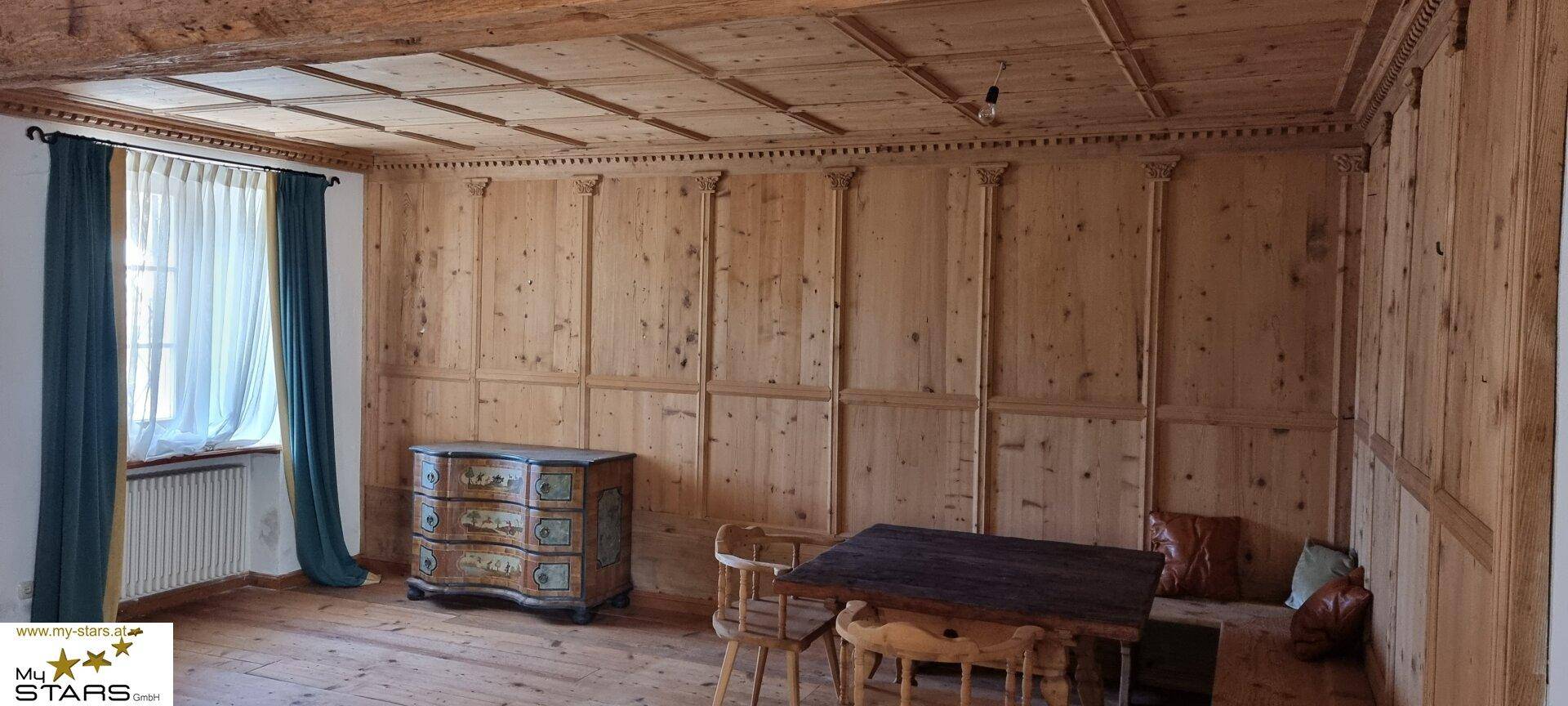 Raum mit Holztäfelung, Holzboden und traditionellen Möbeln, hell und einladend.