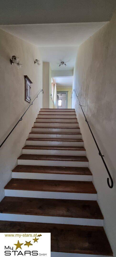Lange Holztreppe mit Metallgeländer führt in die oberen Stockwerke des Hauses.