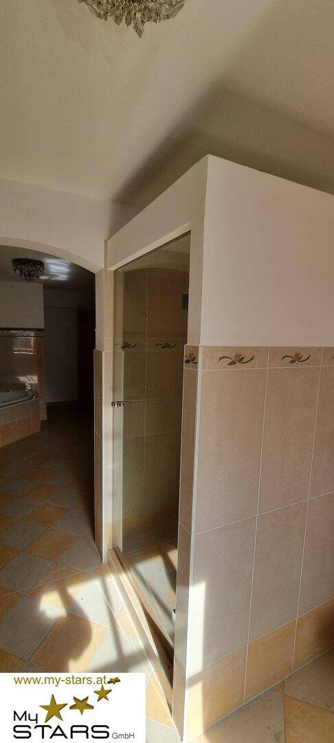Badezimmer mit Duschkabine und gefliesten Wänden, die einen sauberen Eindruck machen.