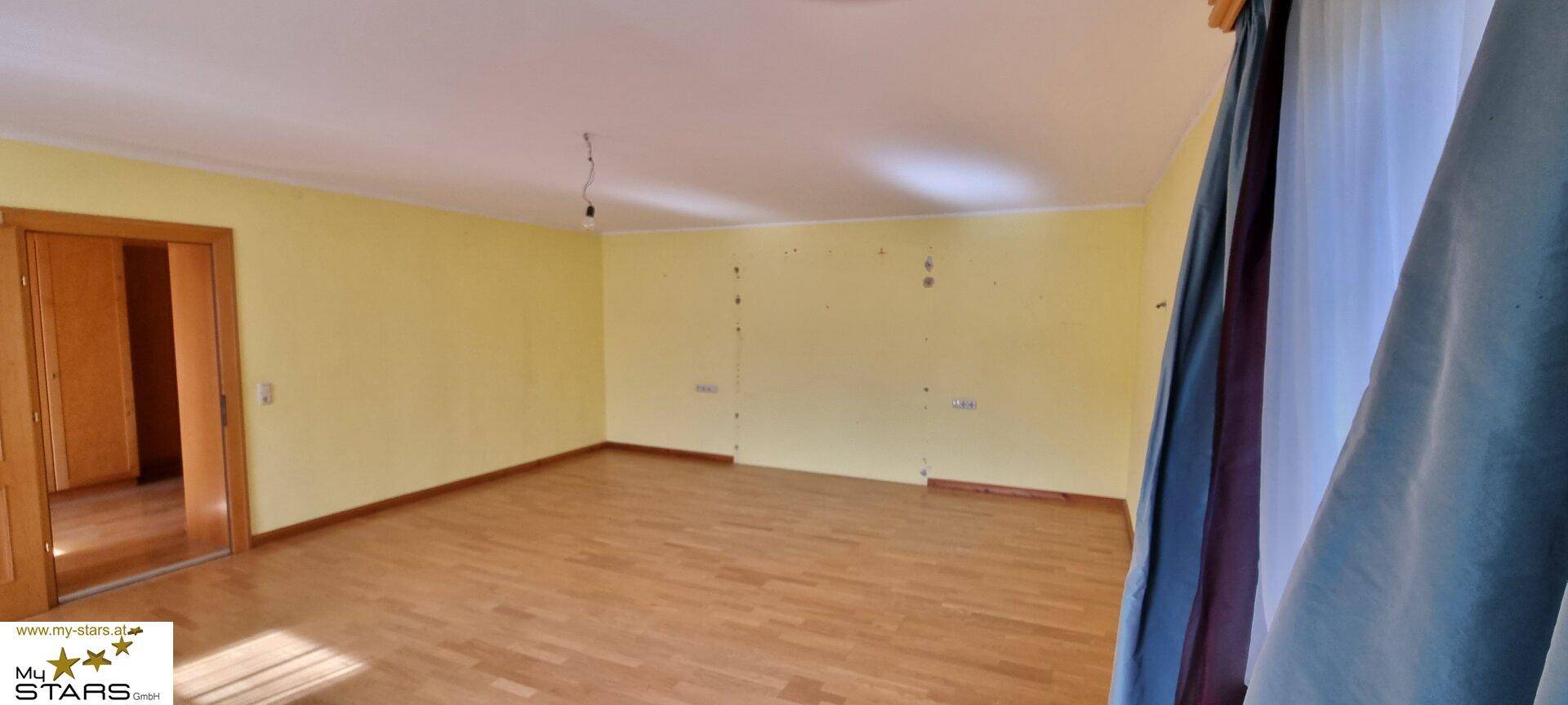 Leeres Zimmer mit gelben Wänden und Holzboden, bereit für individuelle Gestaltung.