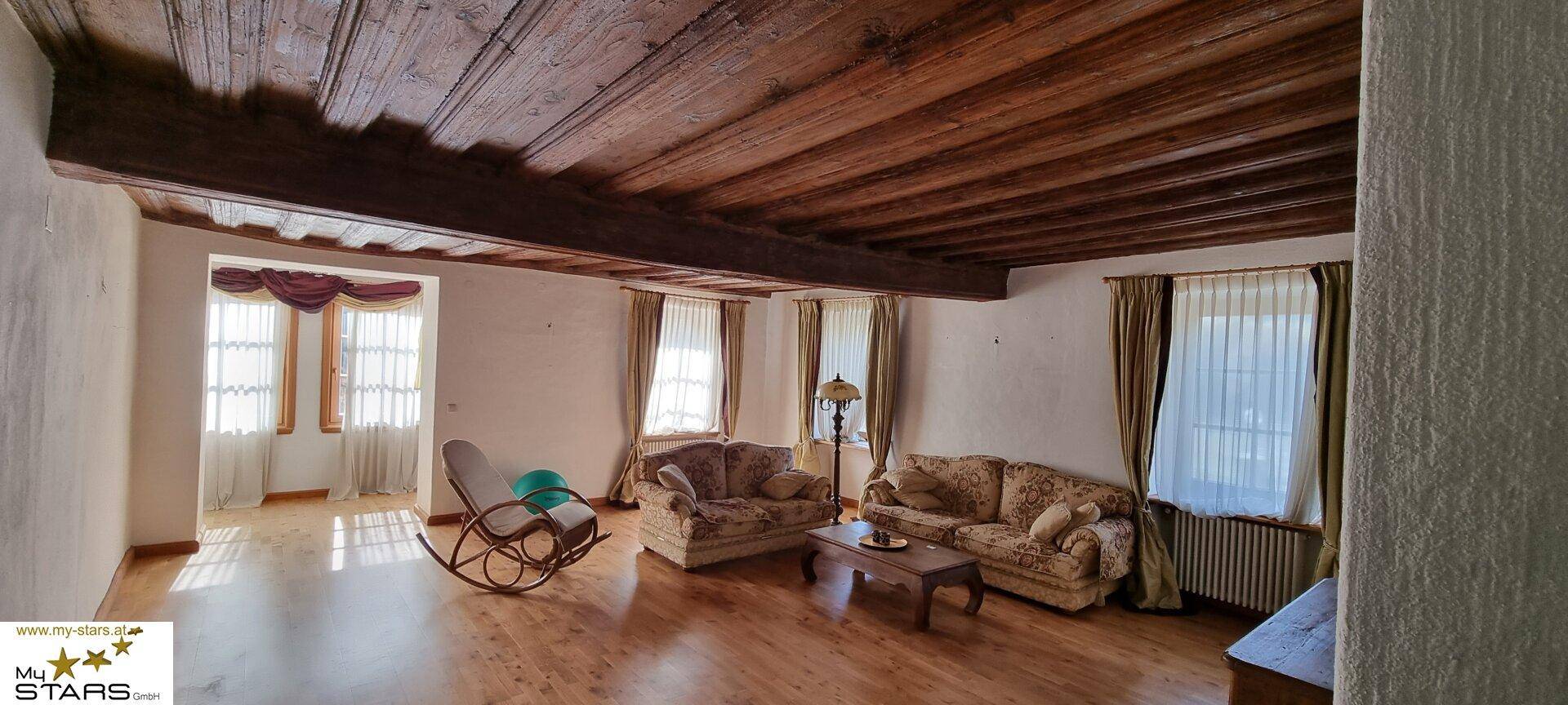 Rustikales Wohnzimmer mit Holzbalkendecke, Parkettboden und traditionellen Möbeln.