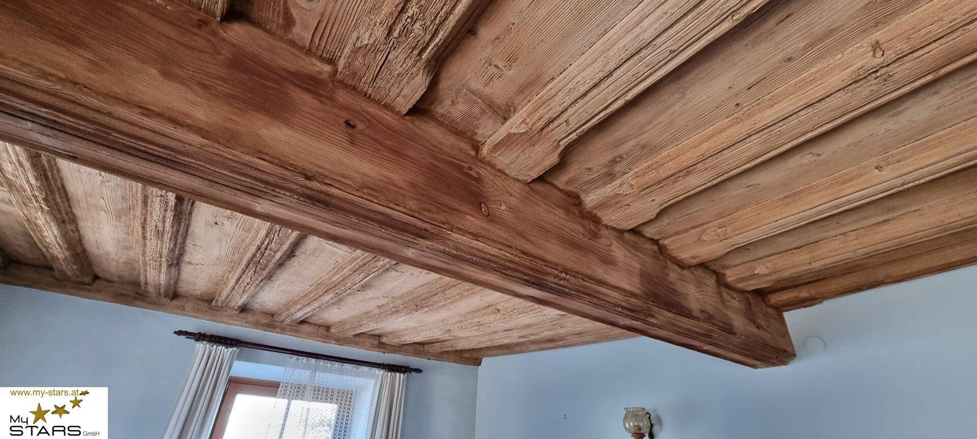 Detailaufnahme einer rustikalen Holzbalkendecke, die den traditionellen Charme unterstreicht.