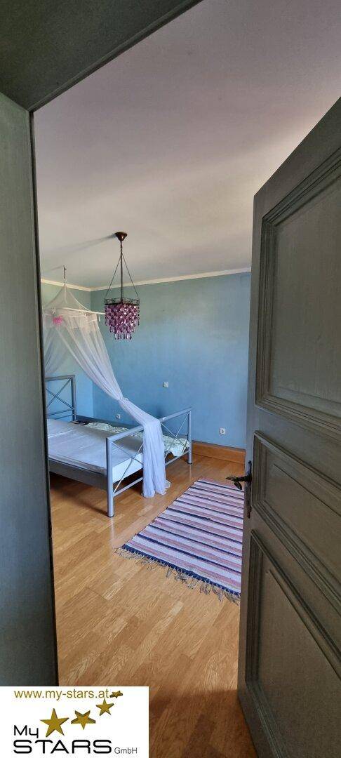 Schlafzimmer mit blau gestrichenen Wänden, Holzboden und einem Himmelbett.