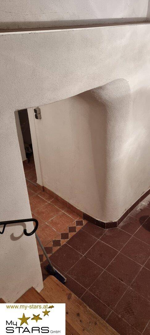 Treppenabgang in den Keller mit gefliestem Boden und weiß verputzten Wänden.