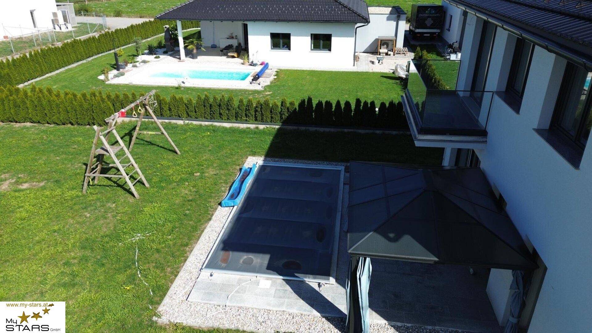 Luftaufnahme des Hauses mit Garten, Pool und überdachtem Terrassenbereich.