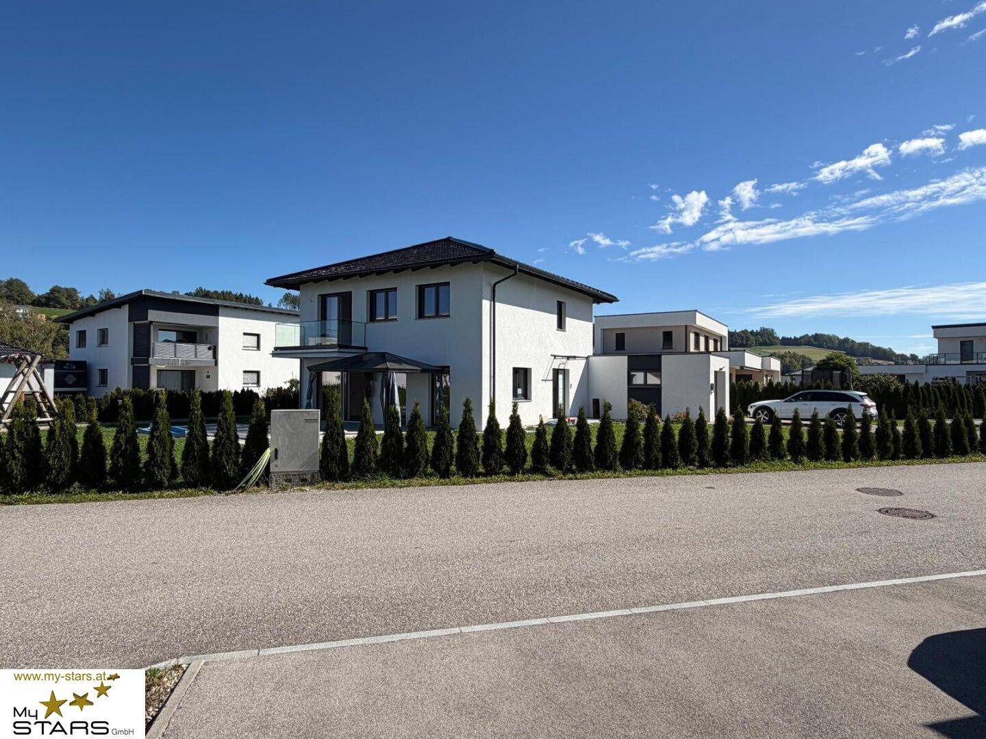 Modernes Einfamilienhaus mit gepflegtem Garten und Hecke in einer ruhigen Wohngegend.