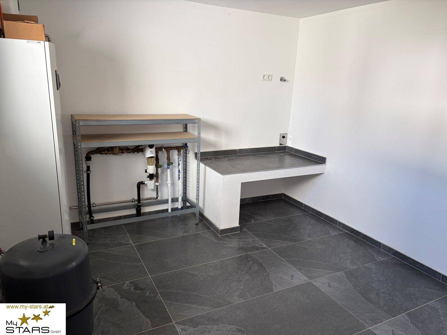 Hauswirtschaftsraum mit Regalen, Arbeitsfläche und Installationen für die Haustechnik.
