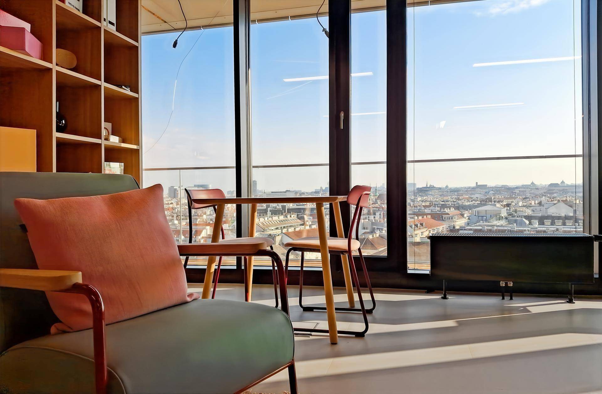 Komfortabler Sessel in einem hellen Bereich mit Stadtblick durch bodentiefe Fenster.
