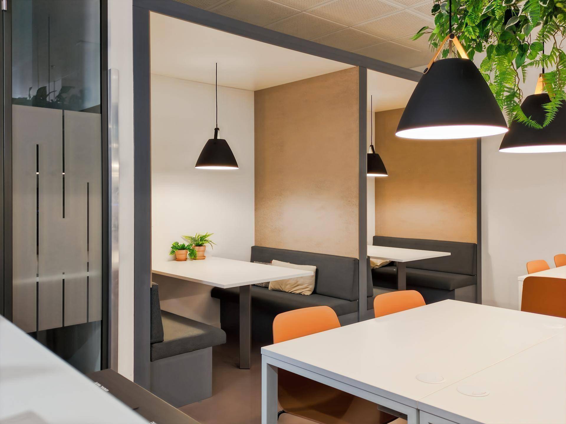 Moderne Bürokabinen mit Tischen und Bänken, ideal für informelle Besprechungen oder Pausen.