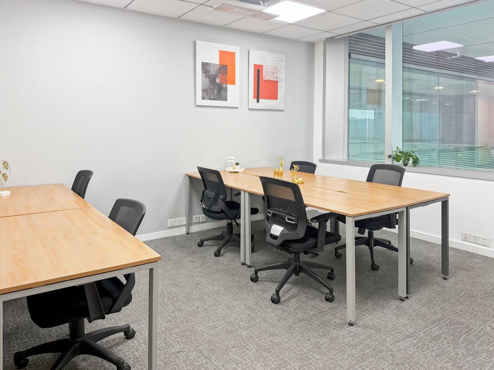 Helles Büro mit Holztischen, ergonomischen Stühlen und großen Fenstern, dekoriert mit moderner Kunst.