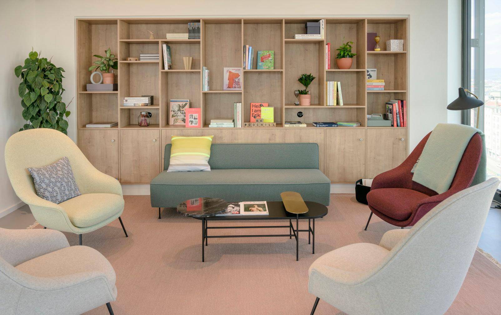 Gemütlicher Loungebereich mit bequemen Sesseln, Sofa und einem großen Bücherregal aus Holz.