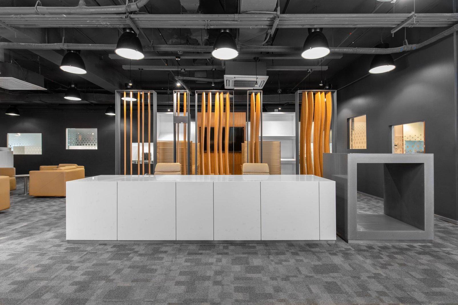 Moderner Empfangsbereich mit langer weißer Theke, dekorativen Holzlamellen und industriellem Design.