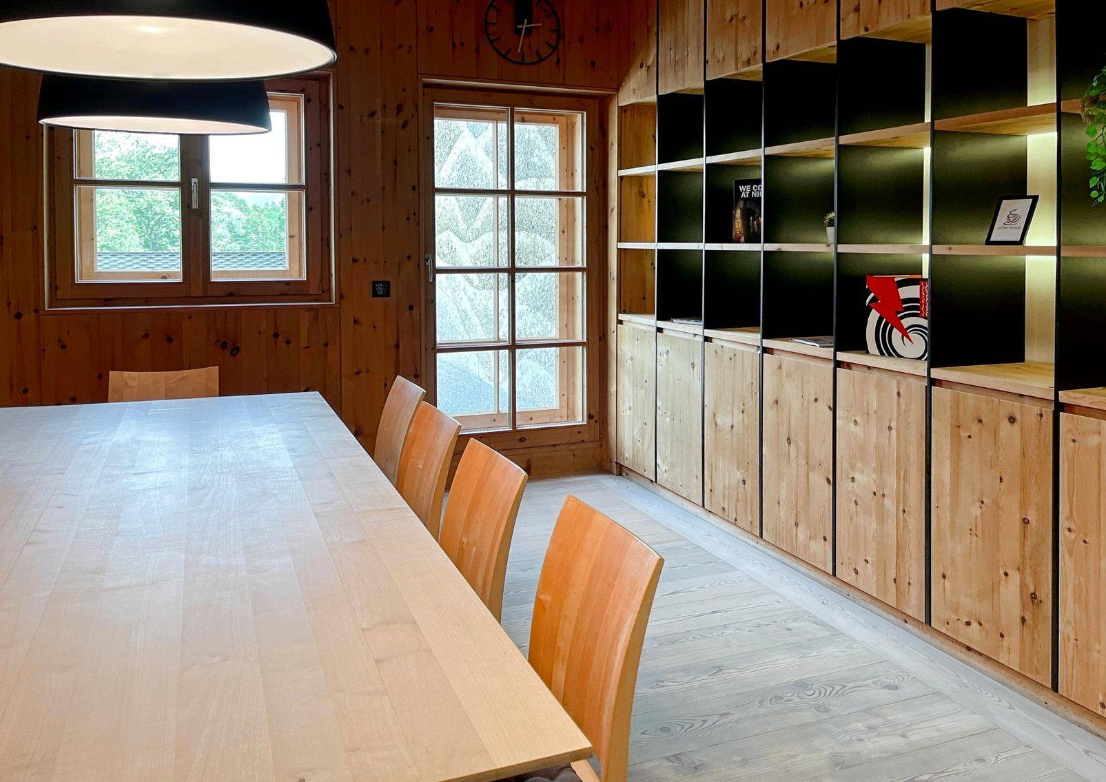 Gemütlicher Essbereich mit Holzwänden, integrierten Regalen und einem großen Holztisch für mehrere Personen.