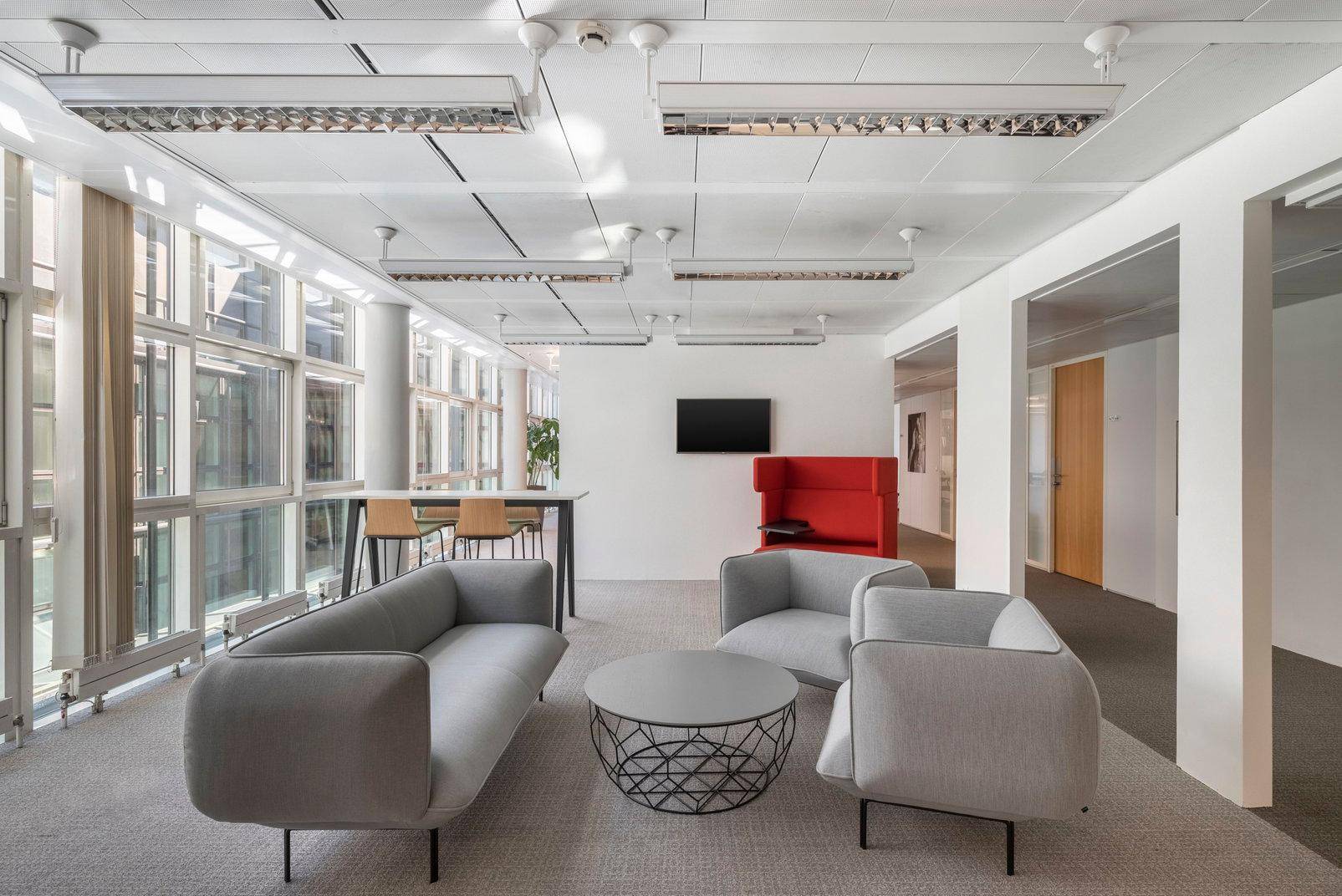 Gemütlicher Loungebereich mit modernen Sofas, Couchtisch und großen Fenstern für viel Tageslicht.
