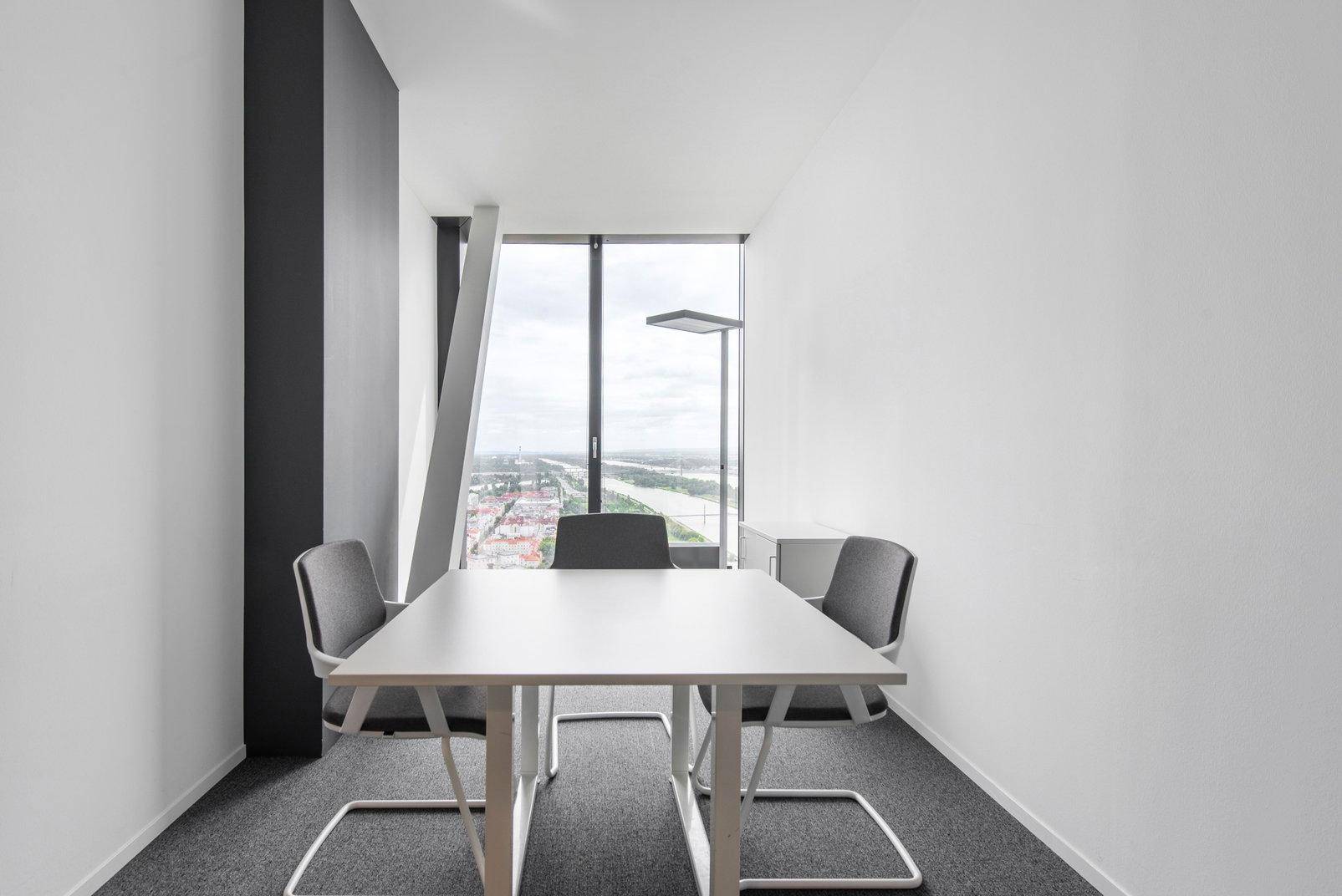 Kleiner Besprechungsraum mit großem Fenster, das einen weiten Blick über die Stadt und den Fluss bietet.