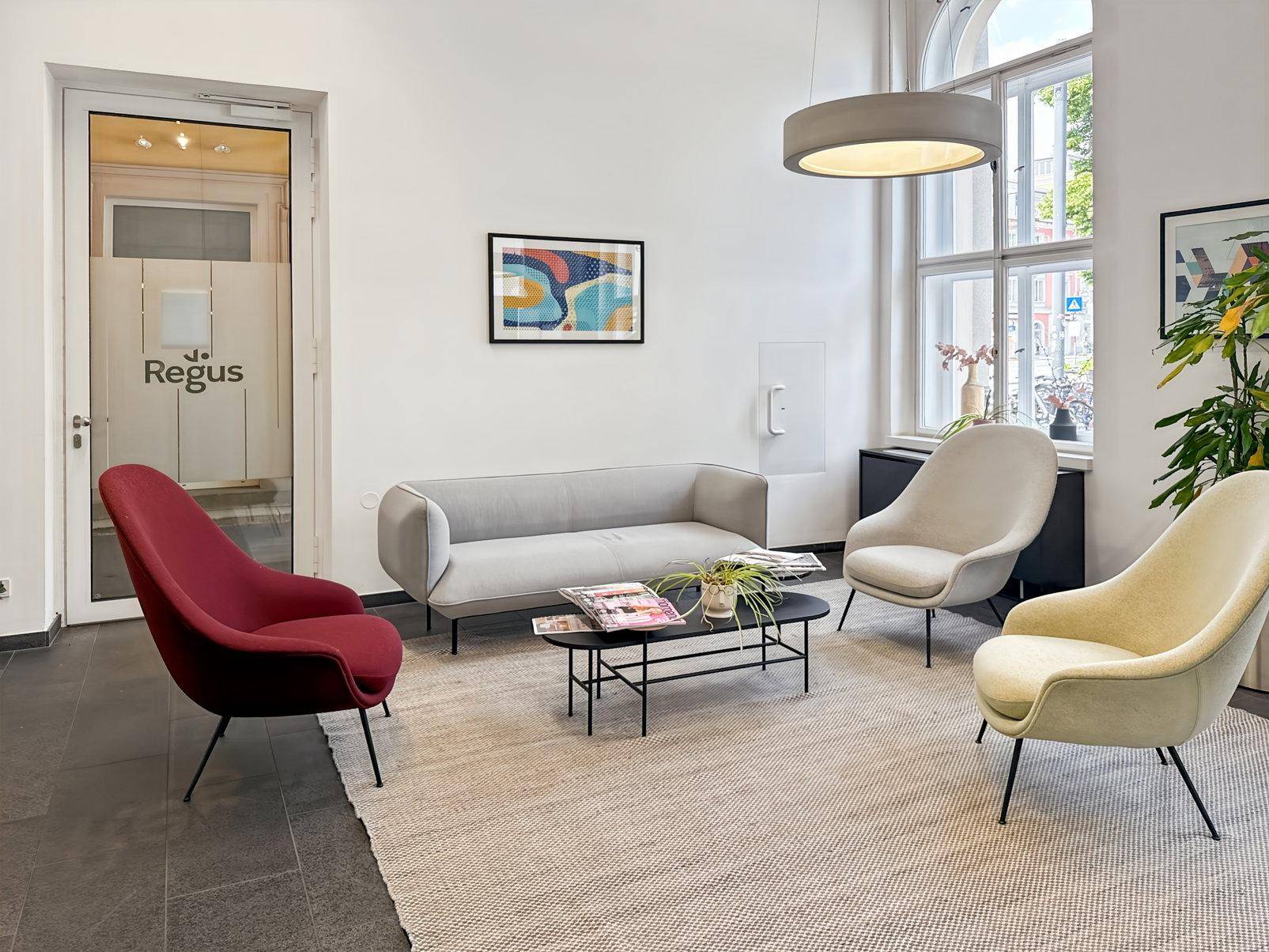 Gemütlicher Wartebereich mit modernen Sitzmöbeln, Teppich und großen Fenstern für viel Tageslicht.