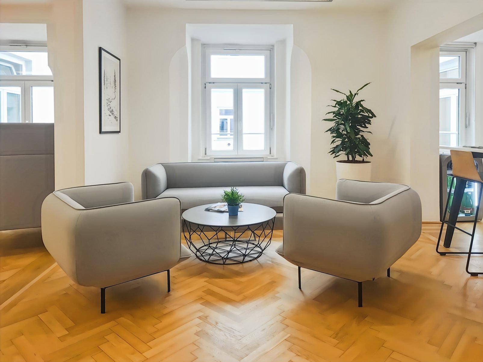 Gemütlicher Loungebereich mit modernen grauen Sofas, einem runden Couchtisch und Fischgrätparkett.