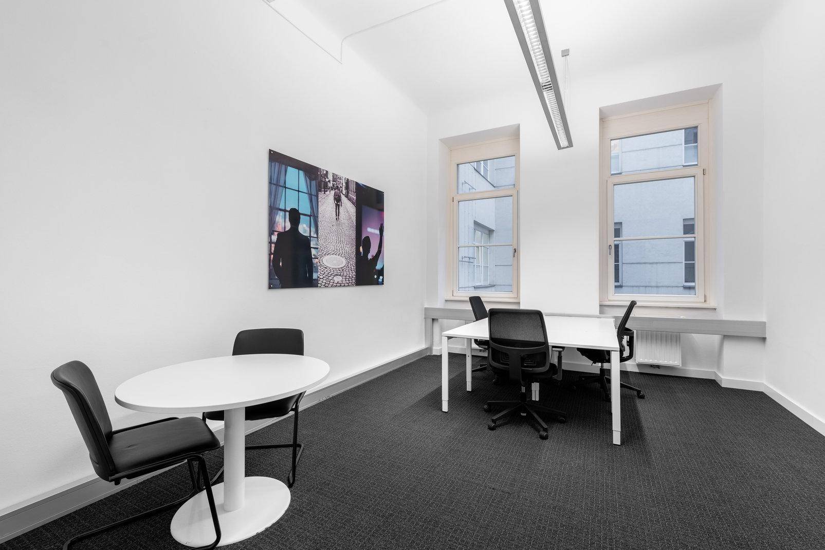 Helles Büro mit zwei Arbeitsbereichen, modernen Möbeln und großen Fenstern, die eine angenehme Arbeitsatmosphäre schaffen.