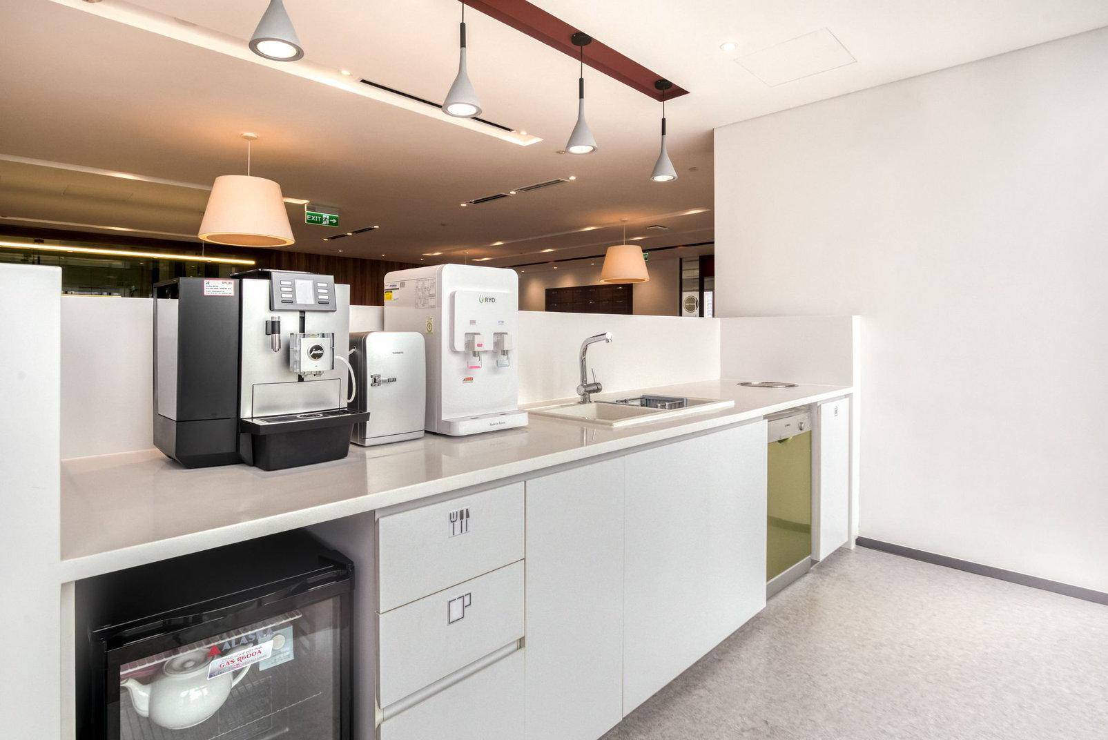 Funktionale Teeküche mit Kaffeemaschine, Wasserspender und Spülmaschine, ideal für die Mitarbeiterversorgung.