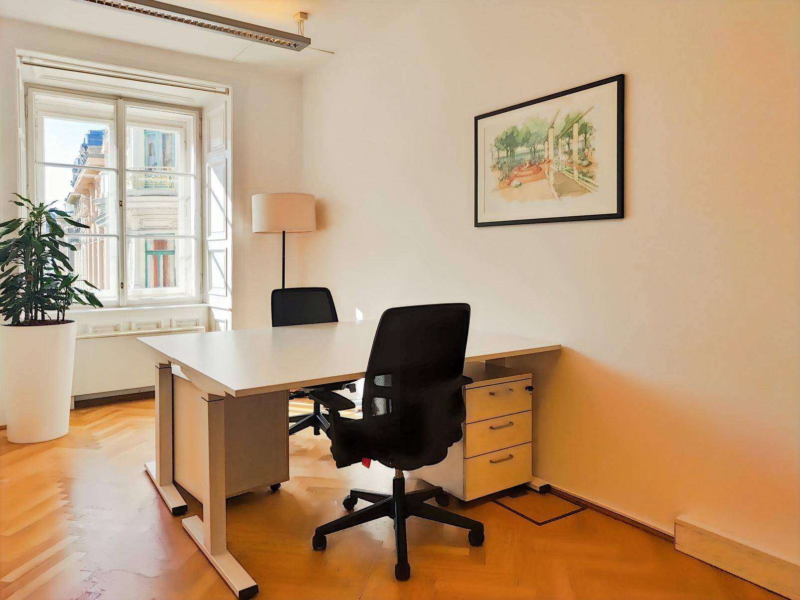 Detailansicht eines hellen Büros mit Schreibtisch, Bürostuhl und einem Fenster mit Blick nach draußen.