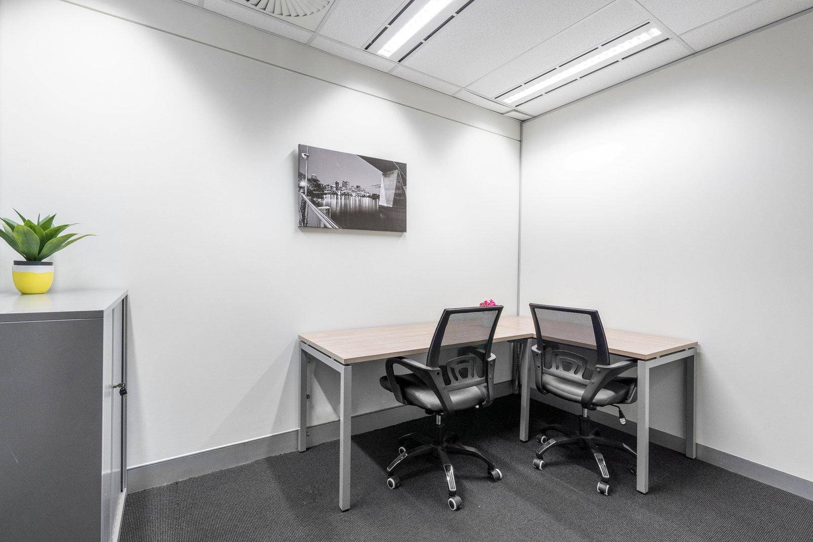 Helles Büro mit zwei Arbeitsplätzen, Teppichboden und einem dekorativen Wandbild.