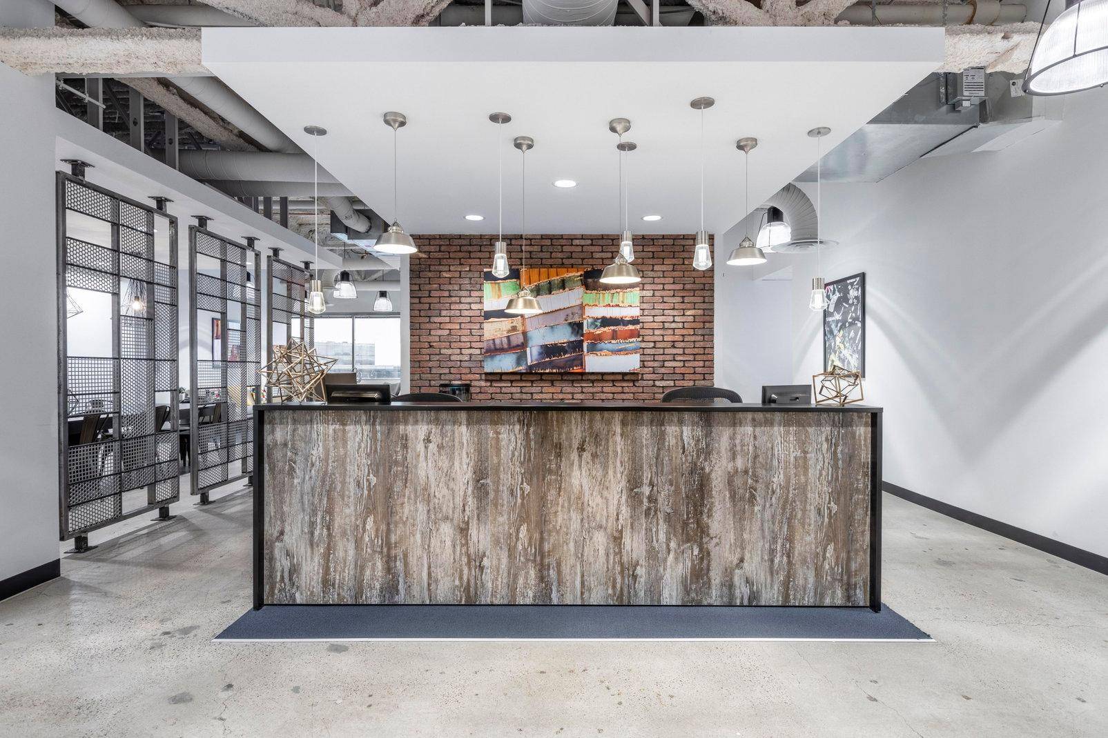 Empfangsbereich mit Holztheke, unverputzter Ziegelwand und industriellem Design.
