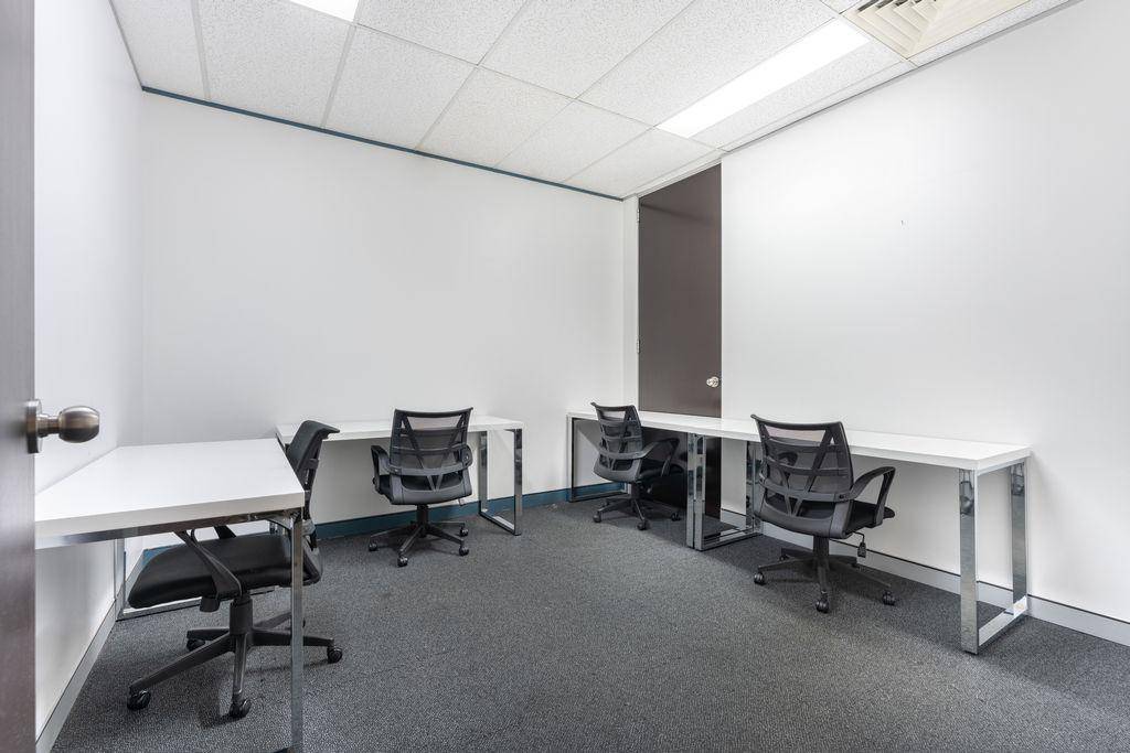Kompaktes Büro mit mehreren Schreibtischen und Bürostühlen, ideal für konzentriertes Arbeiten.