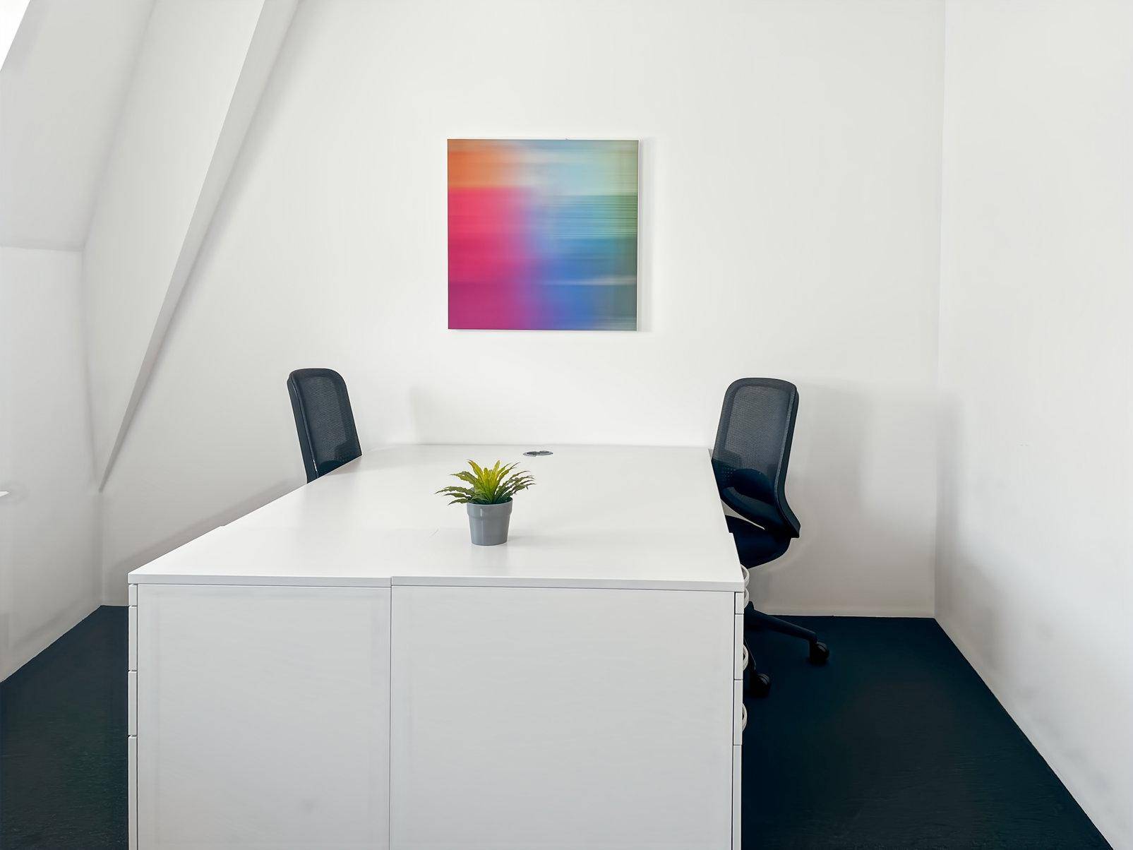 Helles Büro mit Dachschräge, weißem Schreibtisch und zwei Bürostühlen, ideal für konzentriertes Arbeiten.
