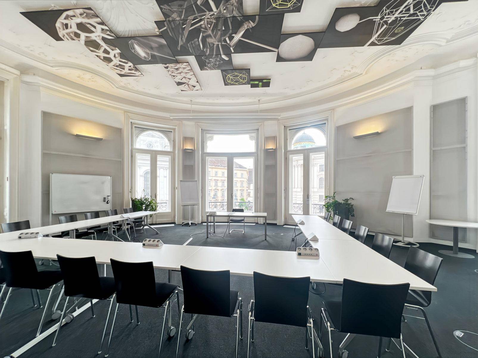 Großer Konferenzraum mit U-förmiger Bestuhlung, Whiteboards und kunstvoller Deckenverzierung.