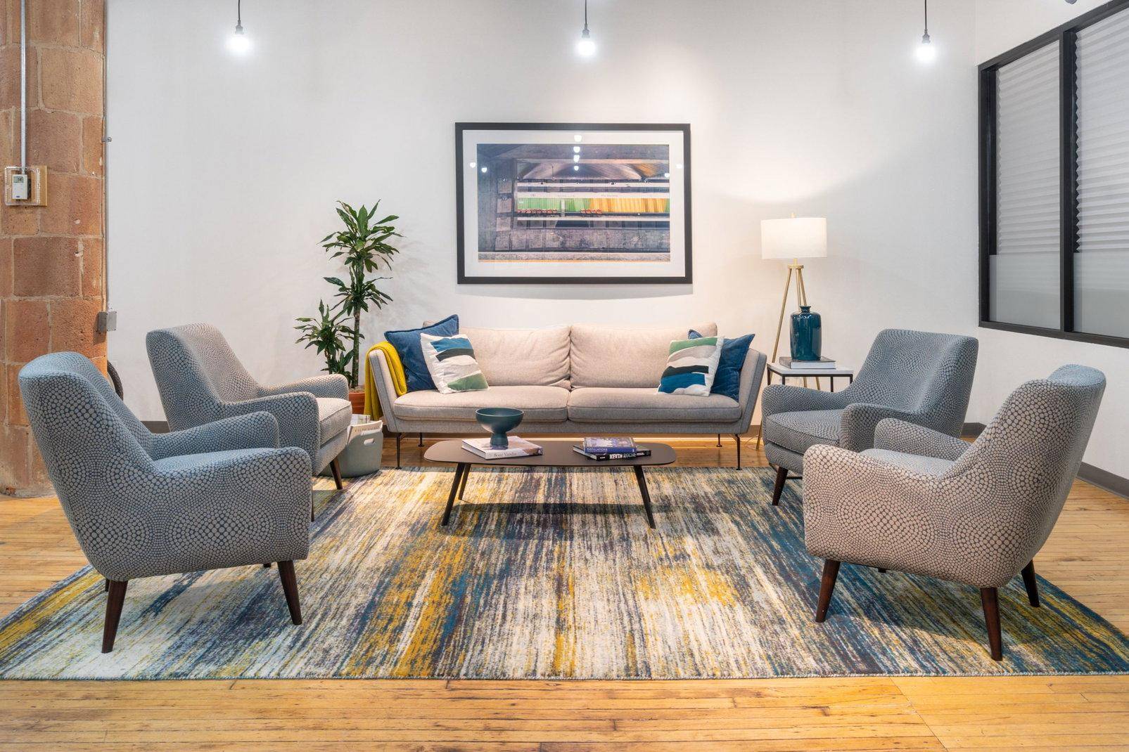 Gemütlicher Loungebereich mit bequemen Sesseln, Sofa und einem farbenfrohen Teppich, ideal zum Entspannen.