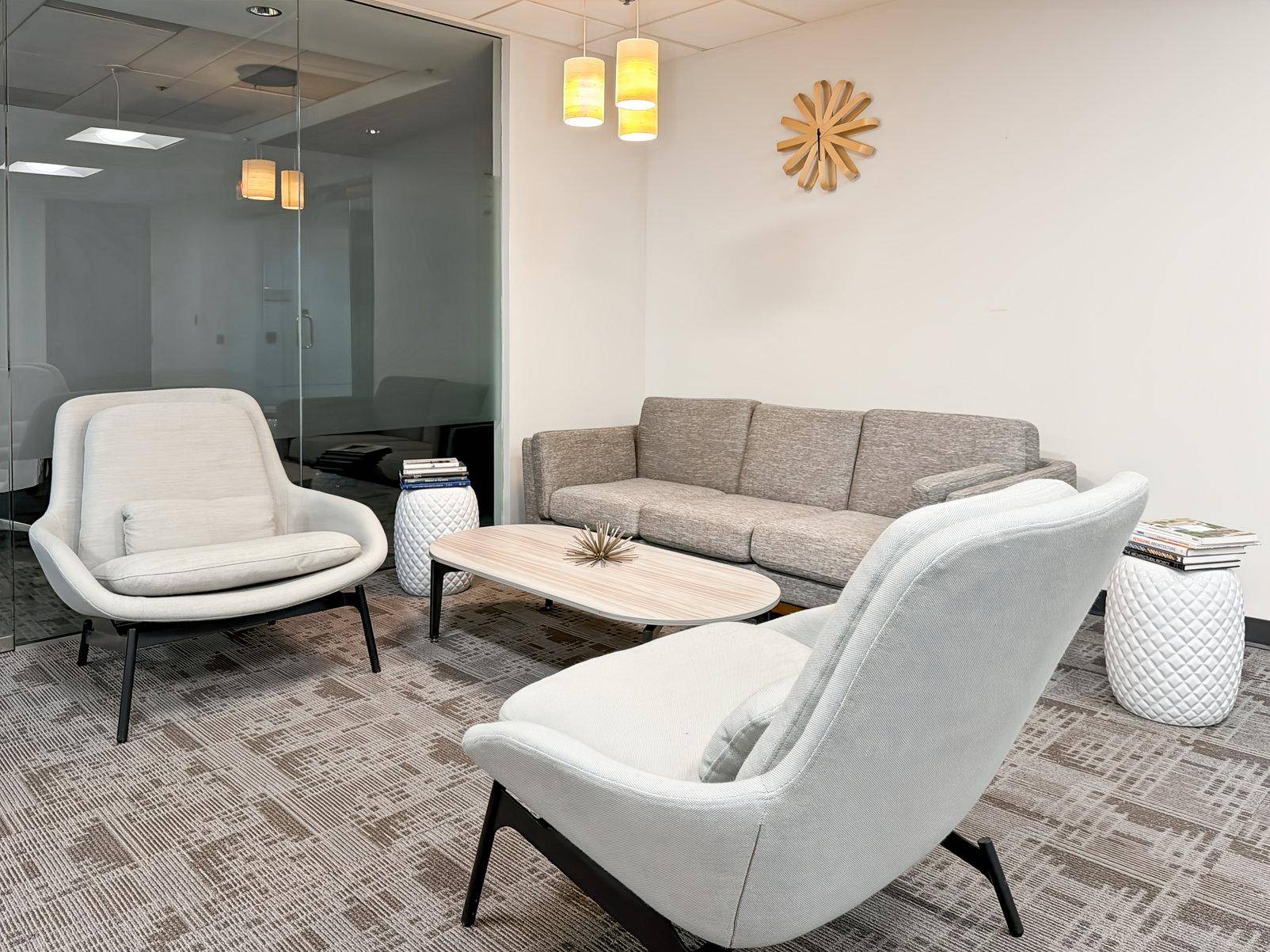 Gemütlicher Loungebereich mit modernen Sesseln, Sofa und Teppichboden, ideal für Wartezeiten und Entspannung.