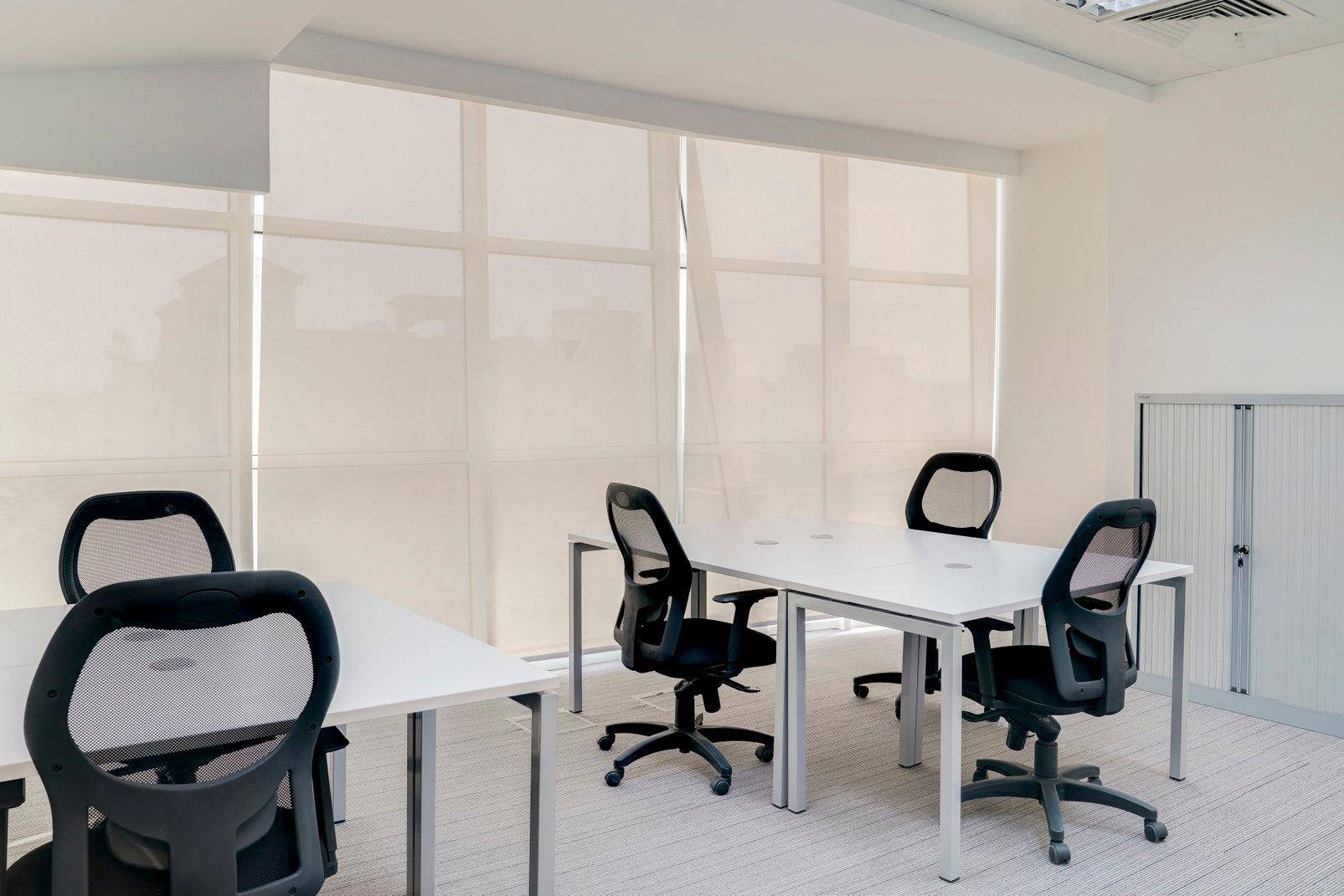 Helles Büro mit mehreren Arbeitsplätzen, großen Fenstern und blickdichten Rollos für Privatsphäre.