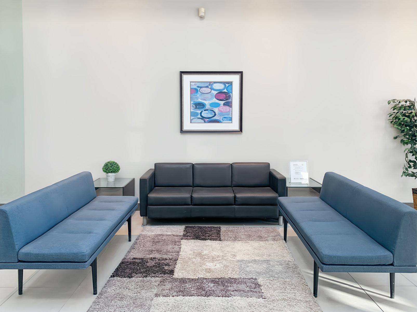 Gemütlicher Loungebereich mit bequemen Sofas, einem Teppich und einem dekorativen Bild an der Wand.