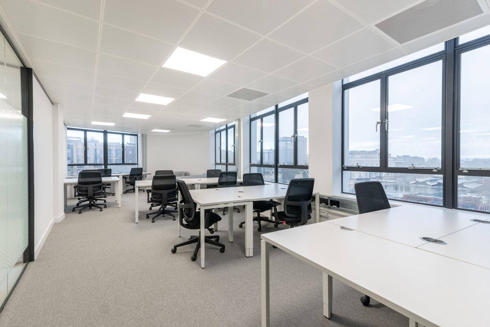 Großes, helles Büro mit vielen Arbeitsplätzen und großen Fenstern, die viel Tageslicht hereinlassen.