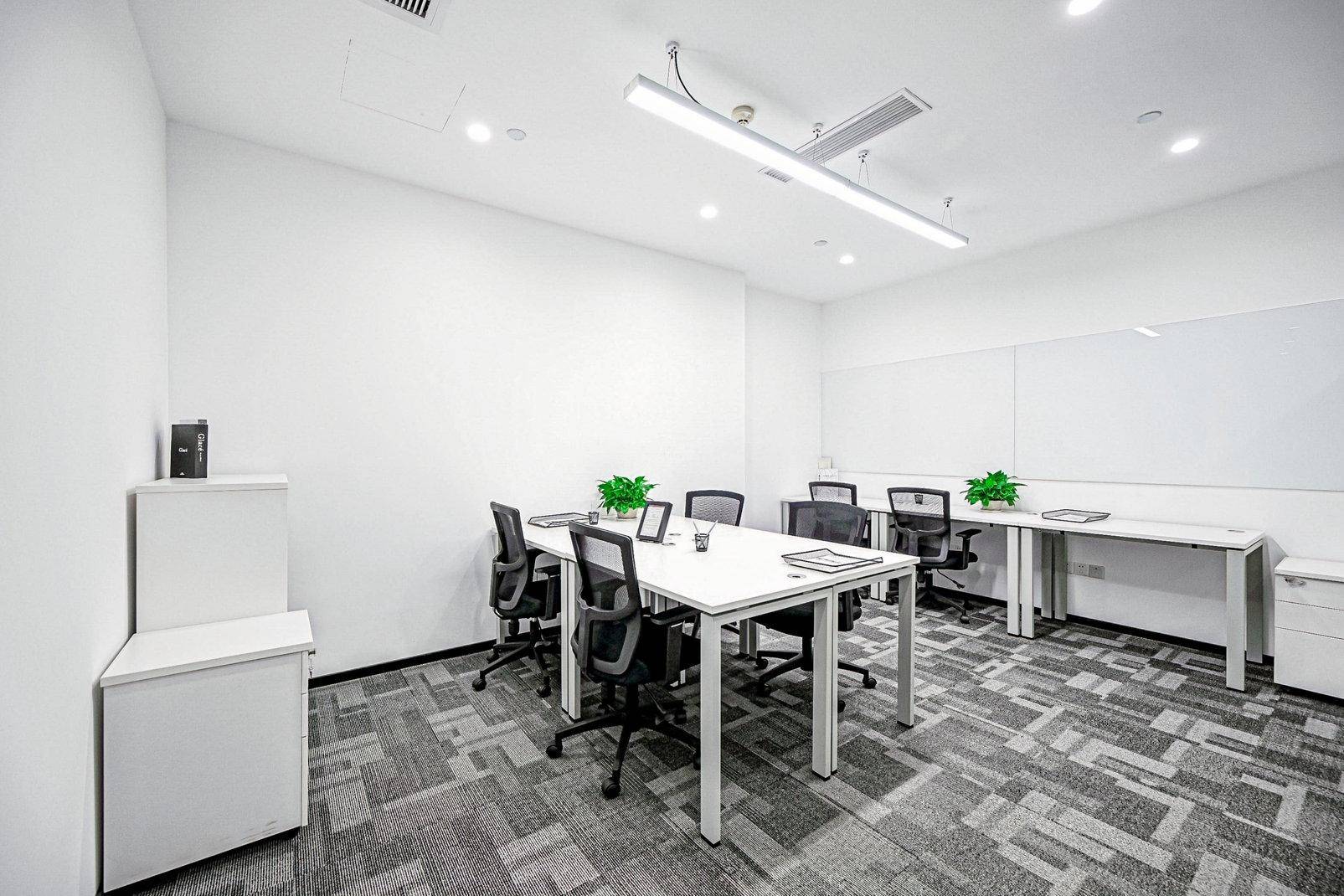 Helles Büro mit einem großen Tisch, mehreren Stühlen, weißen Wänden und einem modernen Teppichboden.