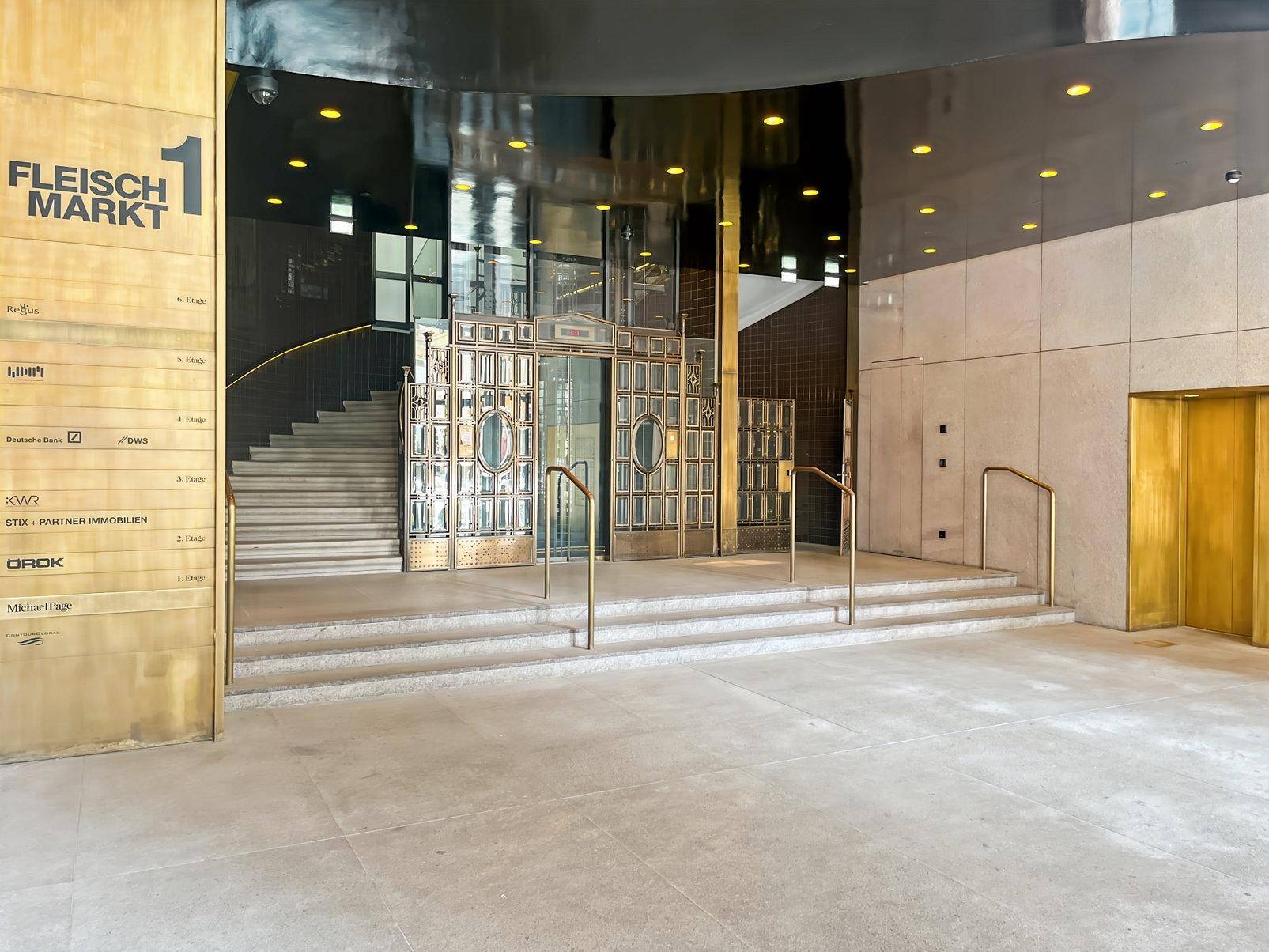 Prunkvolle Eingangshalle eines Gebäudes mit Treppe, Aufzügen und einem Verzeichnis der Mieter.