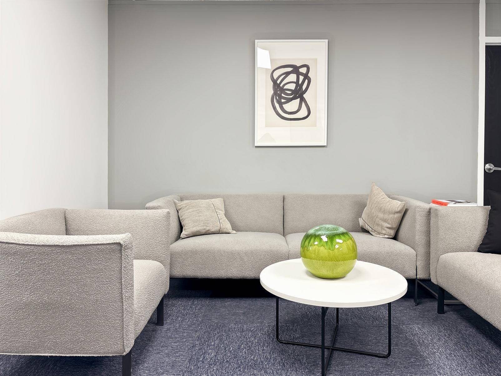 Gemütlicher Loungebereich mit beigen Sofas, einem Couchtisch und moderner Kunst an der grauen Wand.