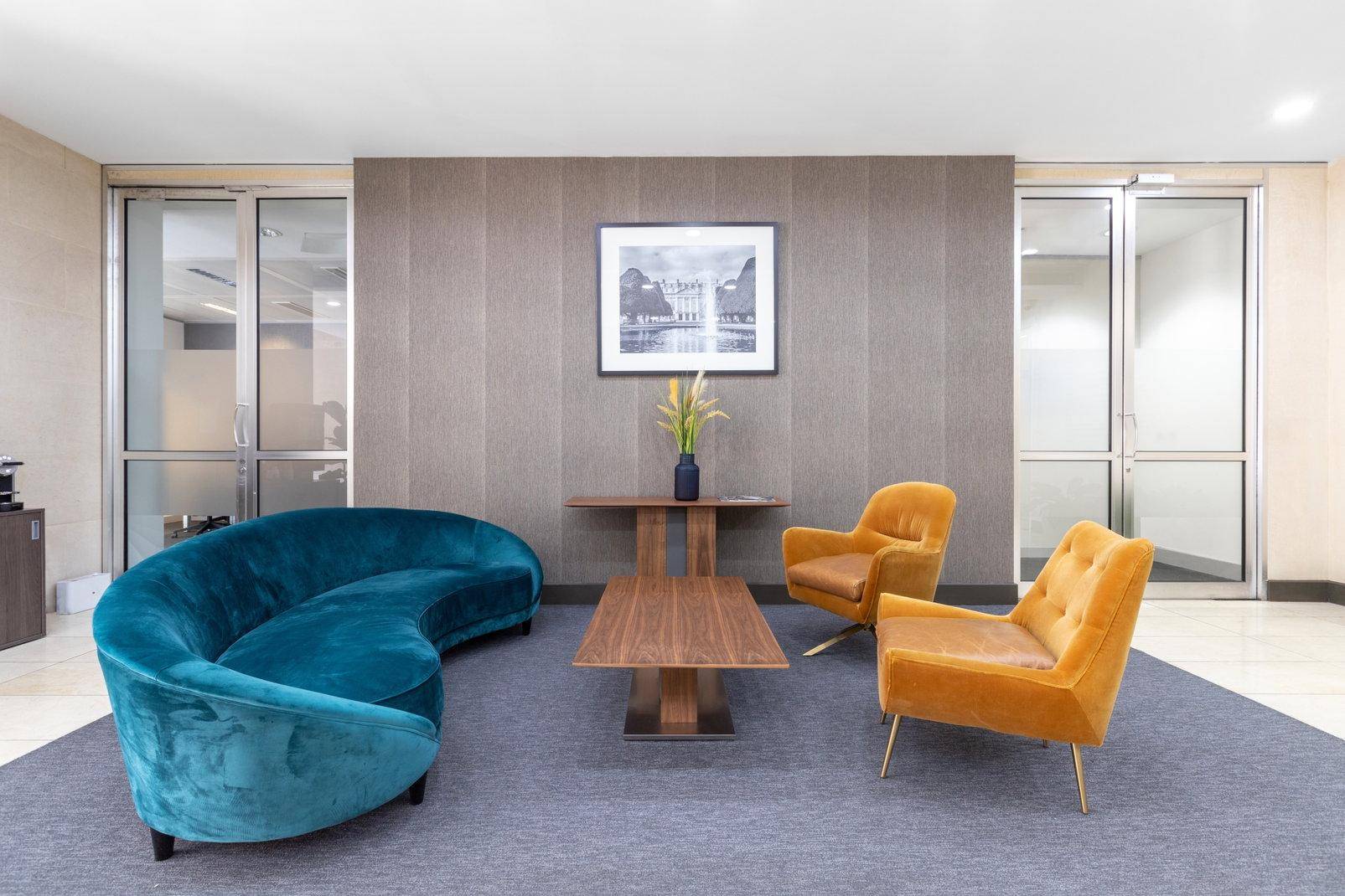 Einladender Loungebereich mit farbenfrohen Samtsofas und Sesseln, ergänzt durch einen eleganten Couchtisch.