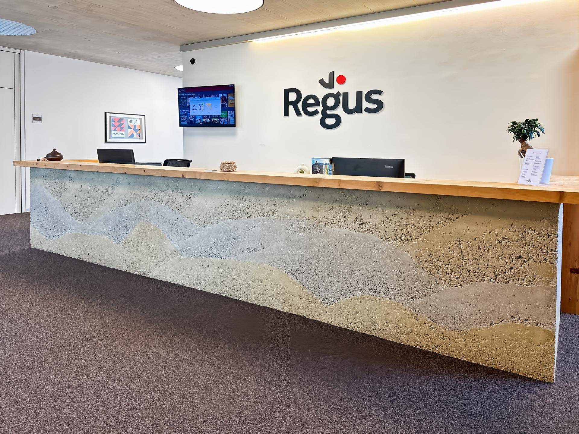 Empfangsbereich mit einer auffälligen Theke aus strukturiertem Material und Firmenlogo an der Wand.