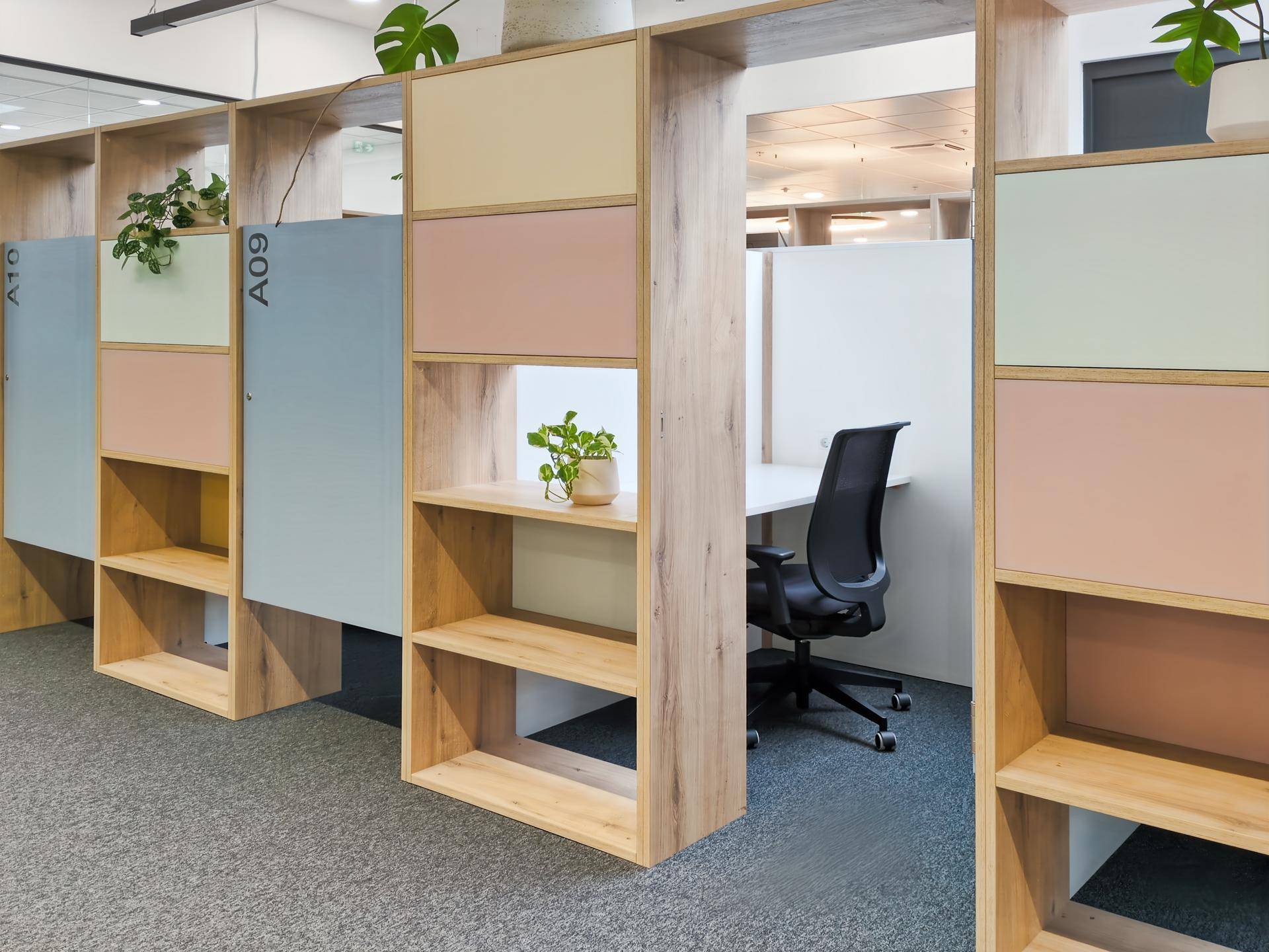 Moderne Arbeitskabinen mit Holzregalen, farbigen Akzenten und Pflanzen für eine angenehme Arbeitsumgebung.