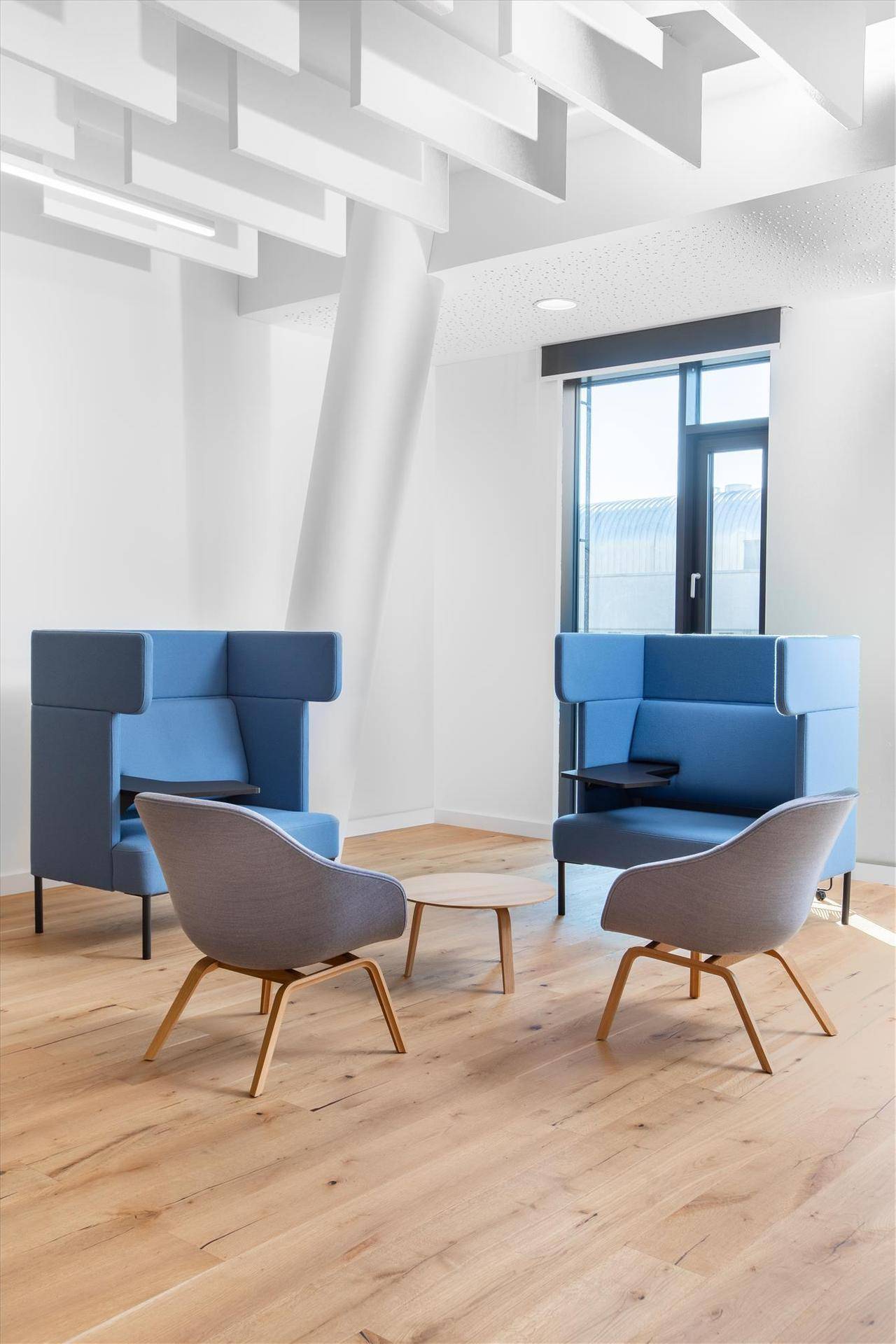 Moderner Loungebereich mit blauen Akustik-Sitzkabinen und Holzboden für entspannte Gespräche.