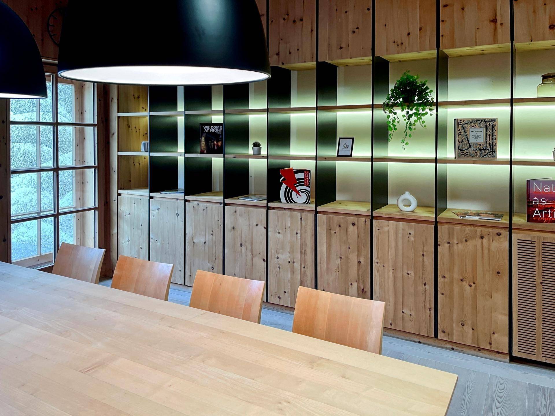 Gemütlicher Essbereich mit Holztisch, Stühlen und beleuchteten Regalen in rustikal-modernem Stil.