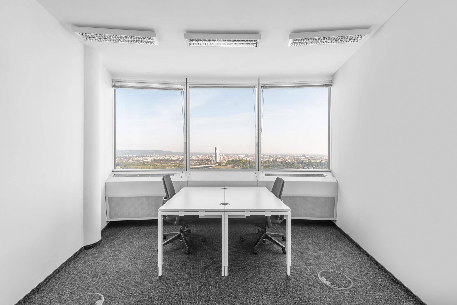 Helles Büro mit zwei Arbeitsplätzen und weitem Blick über die Stadt durch große Fenster.