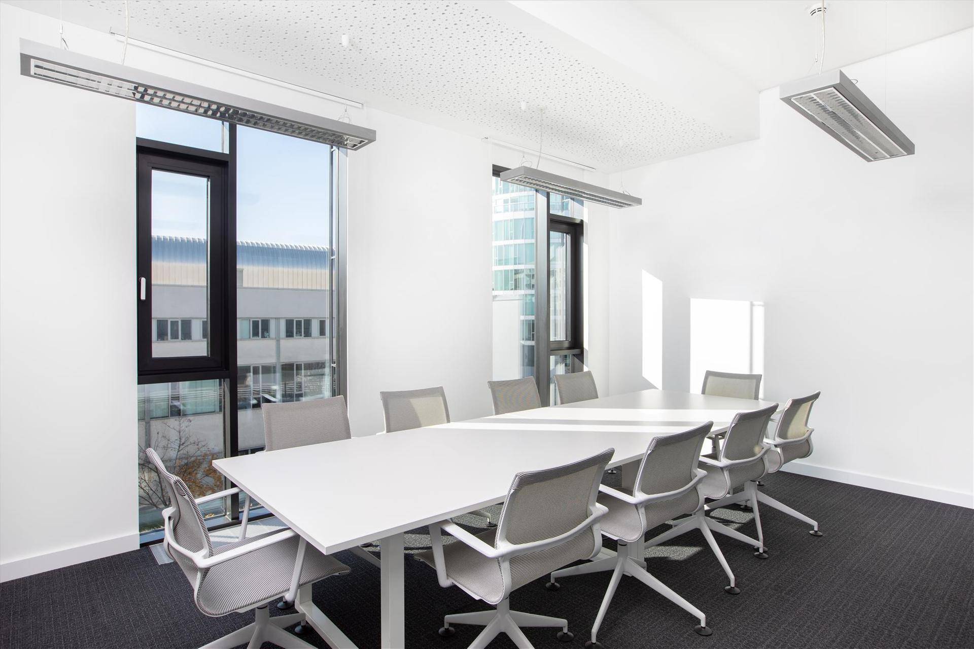 Heller Konferenzraum mit großem weißen Tisch, bequemen Stühlen und weitem Blick auf die Stadt durch große Fenster.
