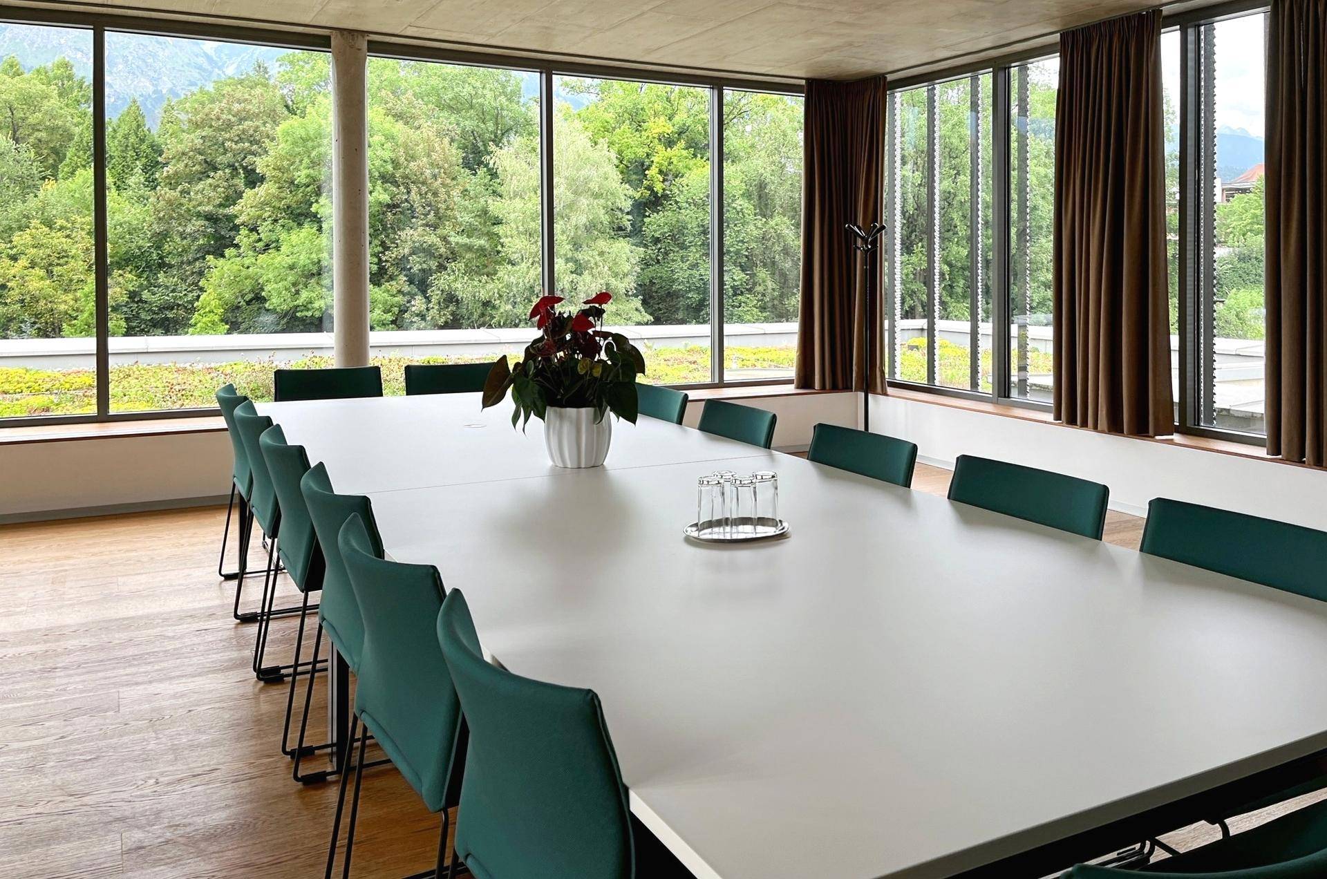 Großer Konferenzraum mit Holzboden, raumhohen Fenstern und weitem Blick ins Grüne.
