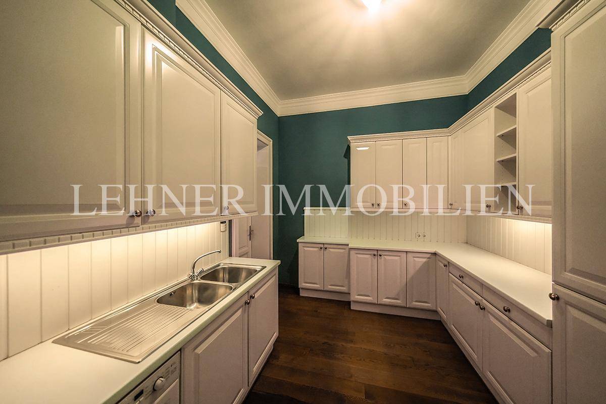 Klassische Küche mit weißen Einbauschränken, Doppelspüle und Arbeitsflächen.