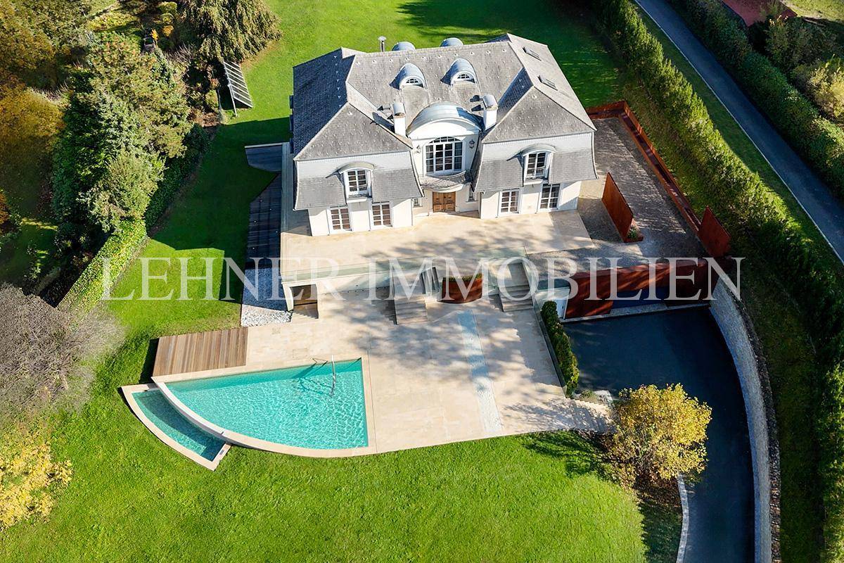 Luftaufnahme der luxuriösen Villa mit weitläufigem Grundstück, Poolbereich und gepflegtem Garten.