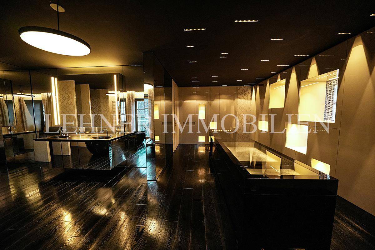 Modernes Luxusbad mit dunklem Holzfußboden, Spiegelflächen und stilvoller Beleuchtung.