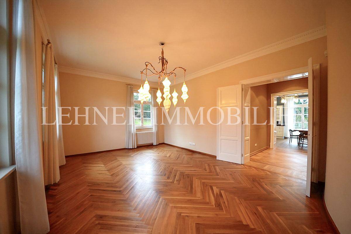 Helles Esszimmer mit Fischgrätparkett, elegantem Kronleuchter und großen Fenstern.